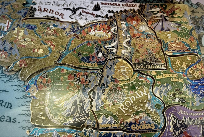 Set of enamel pins depicting Middle-earth map from Lord of the Rings, featuring Arnor, Moria, Rohan, and Gondor, with gold metal outlines, colorful enamel fill, and detailed region illustrations, perfect for collectible fan pins and creative badges
