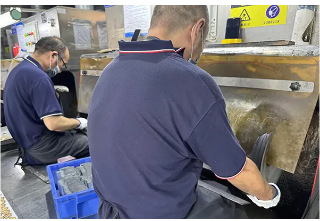 Skilled worker hand-polishing custom metal coins to achieve a smooth and shiny finish.