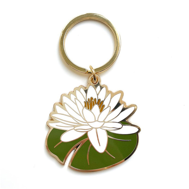 Gold-rimmed enamel keychain featuring a white water lily flower on green lily pad