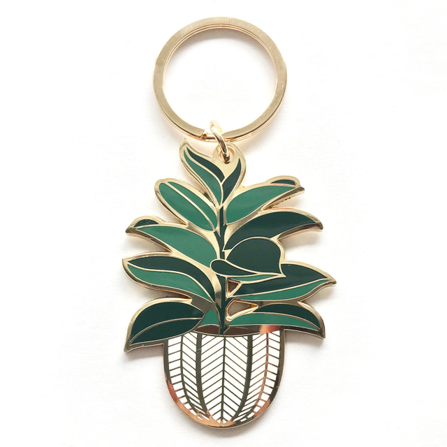 Gold-rimmed enamel keychain featuring a lush green houseplant in a woven basket pot