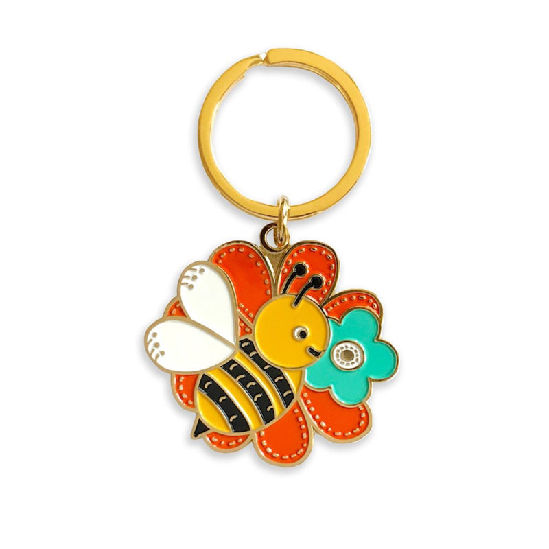 CUGLE cute anime keychain featuring a happy bee on orange and turquoise flowers, hard enamel with gold plating