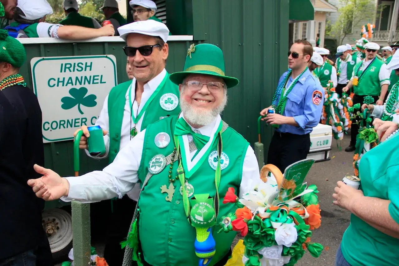 Joyful crowd celebrating St. Patrick's Day parade in green hats, shamrock face paint, and festive outfits on city street
