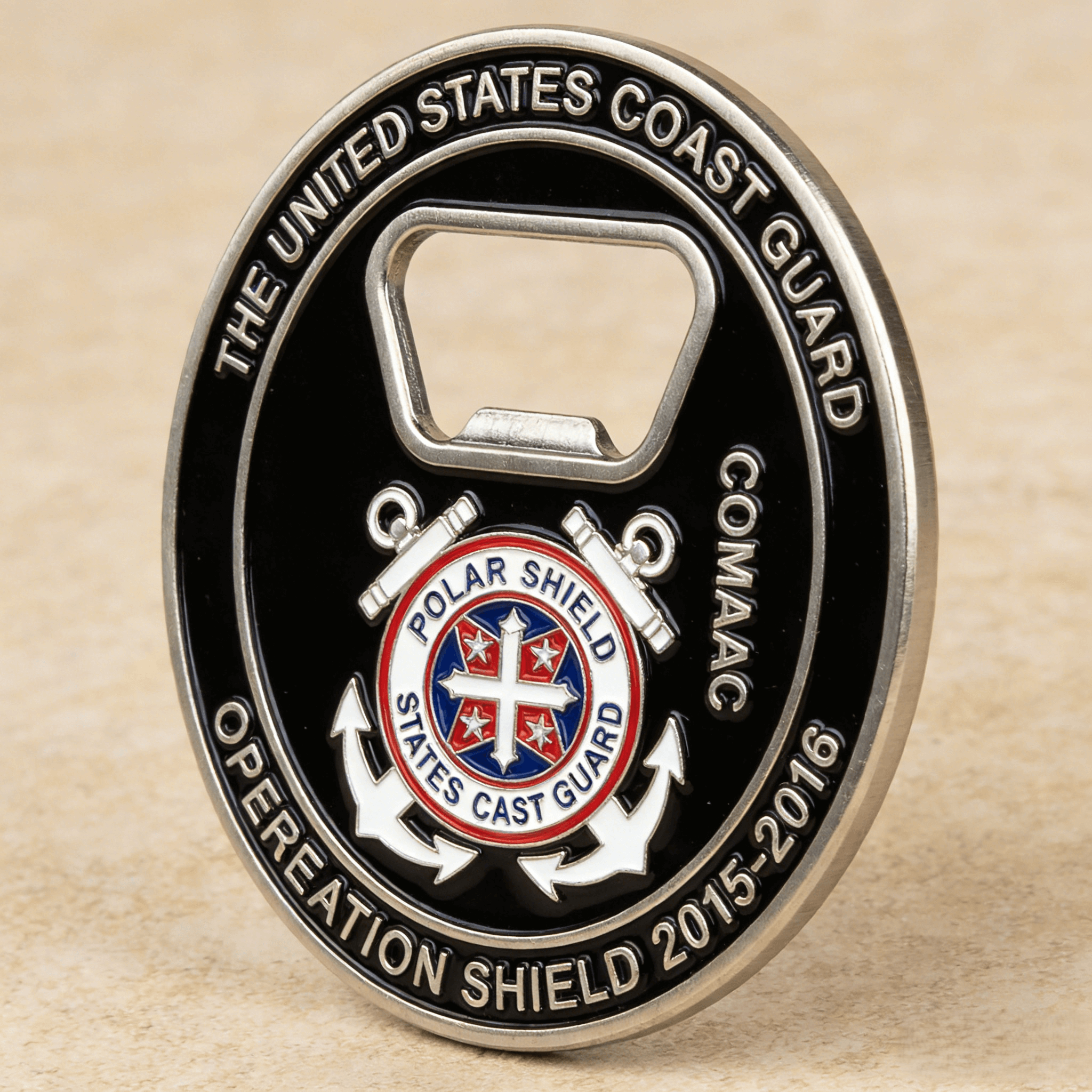 Custom US Coast Guard challenge coin bottle opener with Operation Shield 2015–2016 engraving, COMDAC marking, central shield emblem, and durable metal construction for military commemorative use
