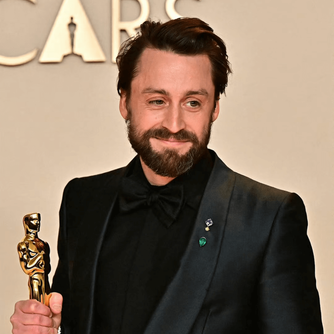 Kieran Culkin wearing a lapel pin with a black velvet tuxedo at the 97th Academy Awards, showcasing proper lapel pin styling for formal red carpet events.